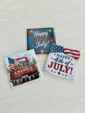 Three magnets with 4th of July designs on a light wooden surface.