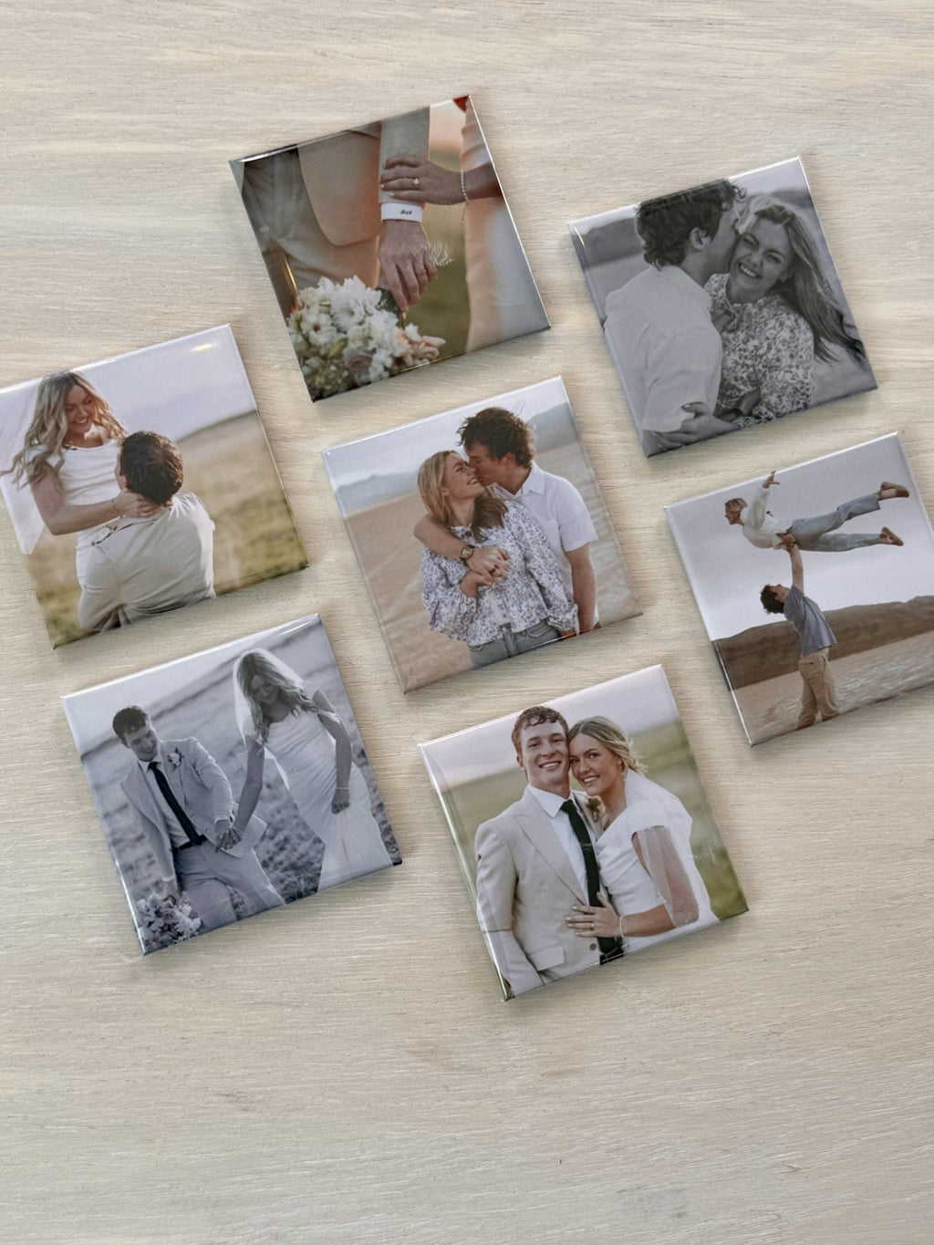 Set of seven photo magnets with various images on a wooden surface.