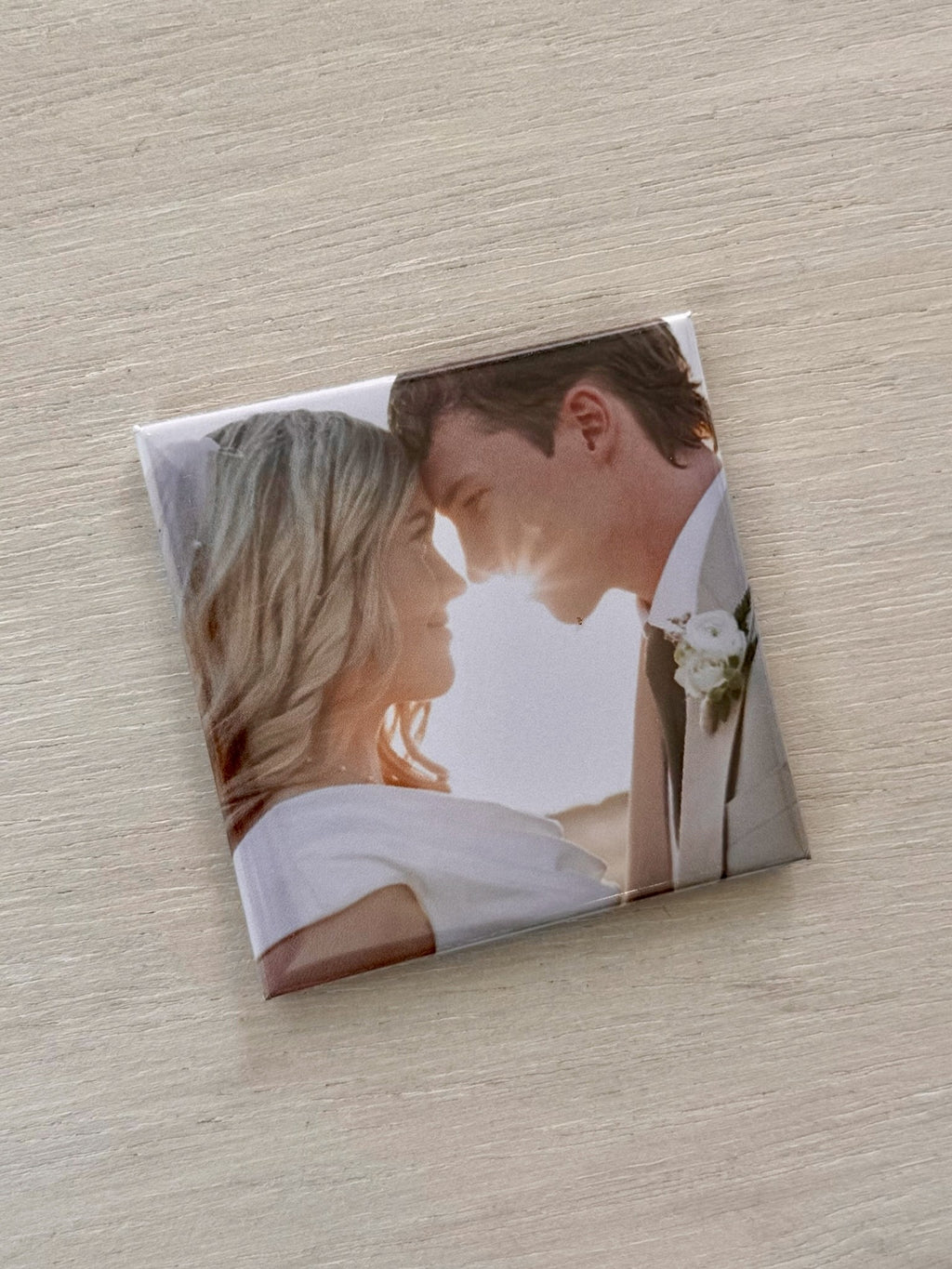 Square photo magnet of a couple on a wooden surface.