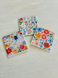 Three floral magnets on a light wooden surface