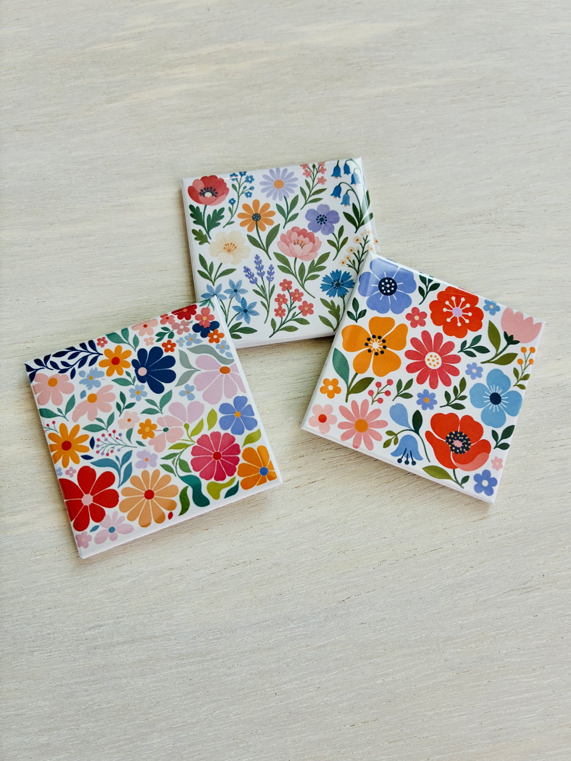 Three floral magnets on a light wooden surface